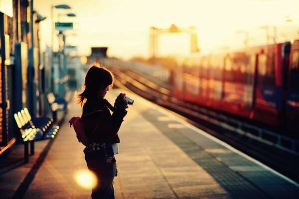 At the train station, a girl takes pictures of a train