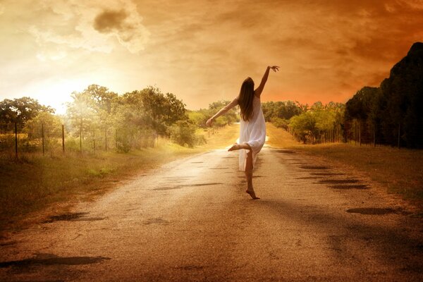 Chica bailando en el camino en medio de la naturaleza