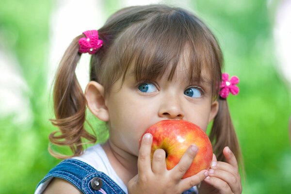 A girl with blue eyes and tails eats an apple