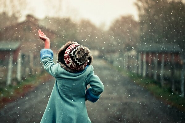 Niña bajo las nevadas atrapa copos de nieve de la mano