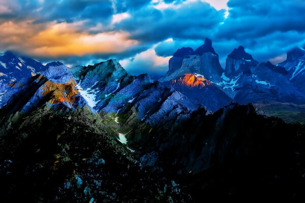 Ungewöhnliche Sonnenuntergangslandschaft vor dem Hintergrund der blauen Berge und Wolken