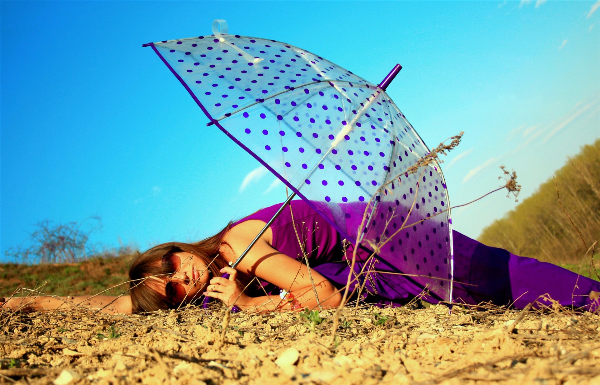 ragazza bruna sdraiata foresta natura terra ombrello occhiali blu cielo