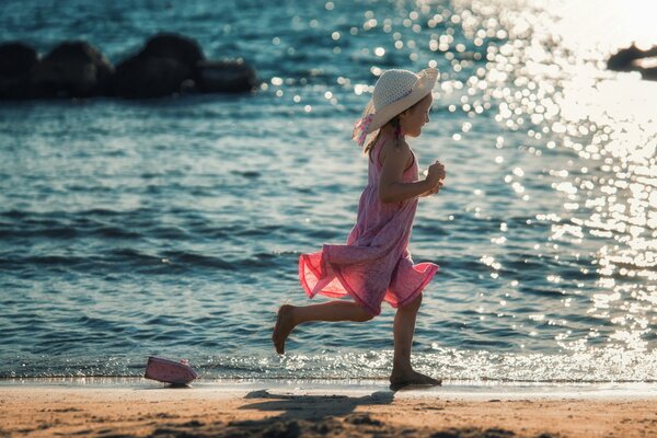 Una niña corre por la orilla tras un barco