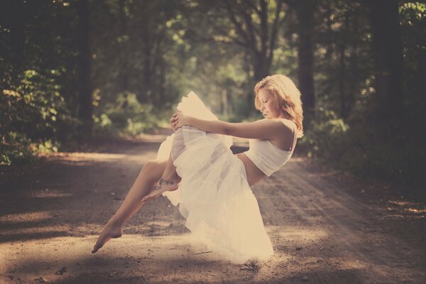 Fille aux pieds nus dans une jupe de ballet planant dans l air sur le fond de la route de la forêt