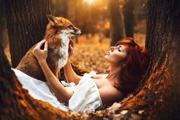 Rousse de la jeune fille pose avec le renard sur la nature