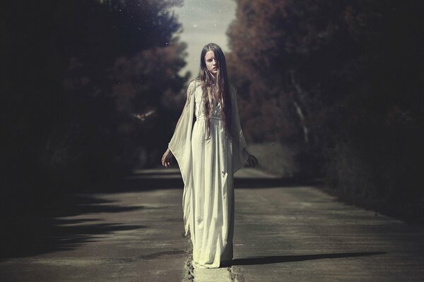 Chica con vestido blanco en medio de la carretera