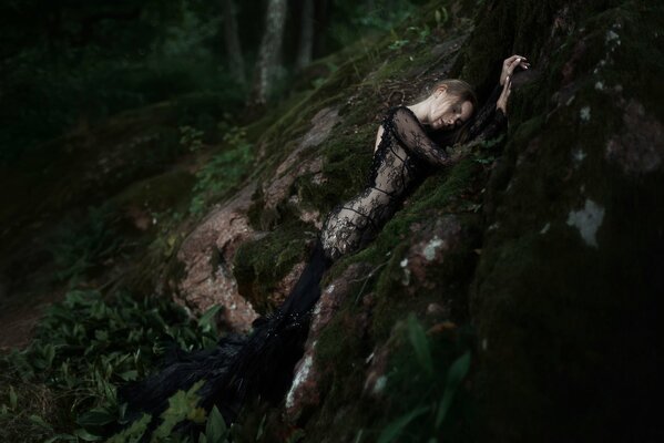 Composition with nature. A girl in a black dress in the forest