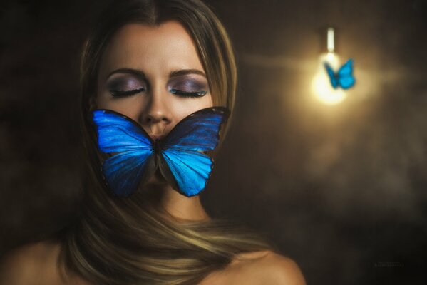 A girl poses with a butterfly on a dark background