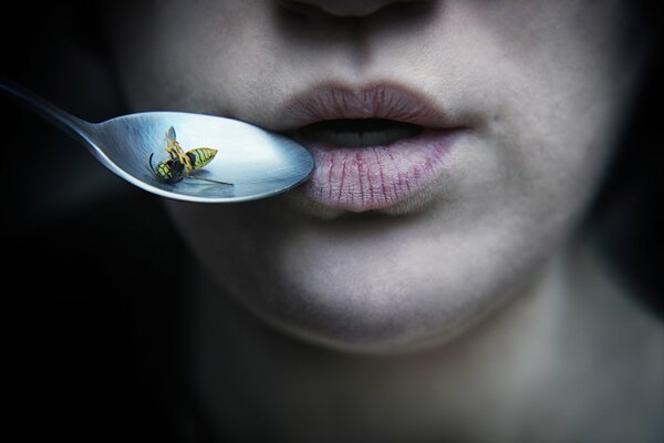 Female lips and a spoon with a bee