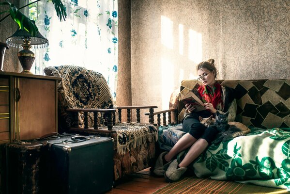 A girl is reading a book sitting on the couch