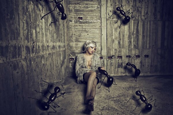 A girl sitting on the sand in a barn with huge ants