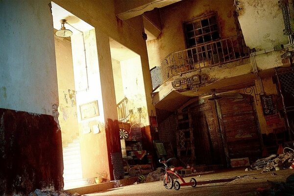 A red tricycle in a ruined house