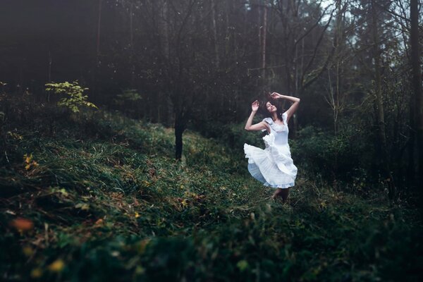 Mädchen im weißen Kleid tanzt im Wald