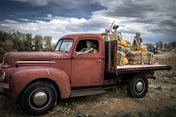 Halloween-Skelette fahren in einem LKW mit Kürbissen und Heu