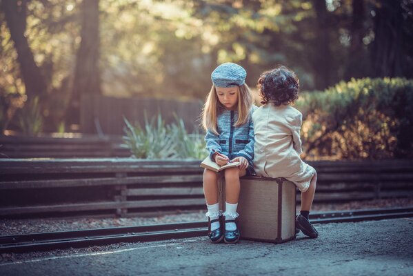 Süße Kinder sitzen auf einem Koffer