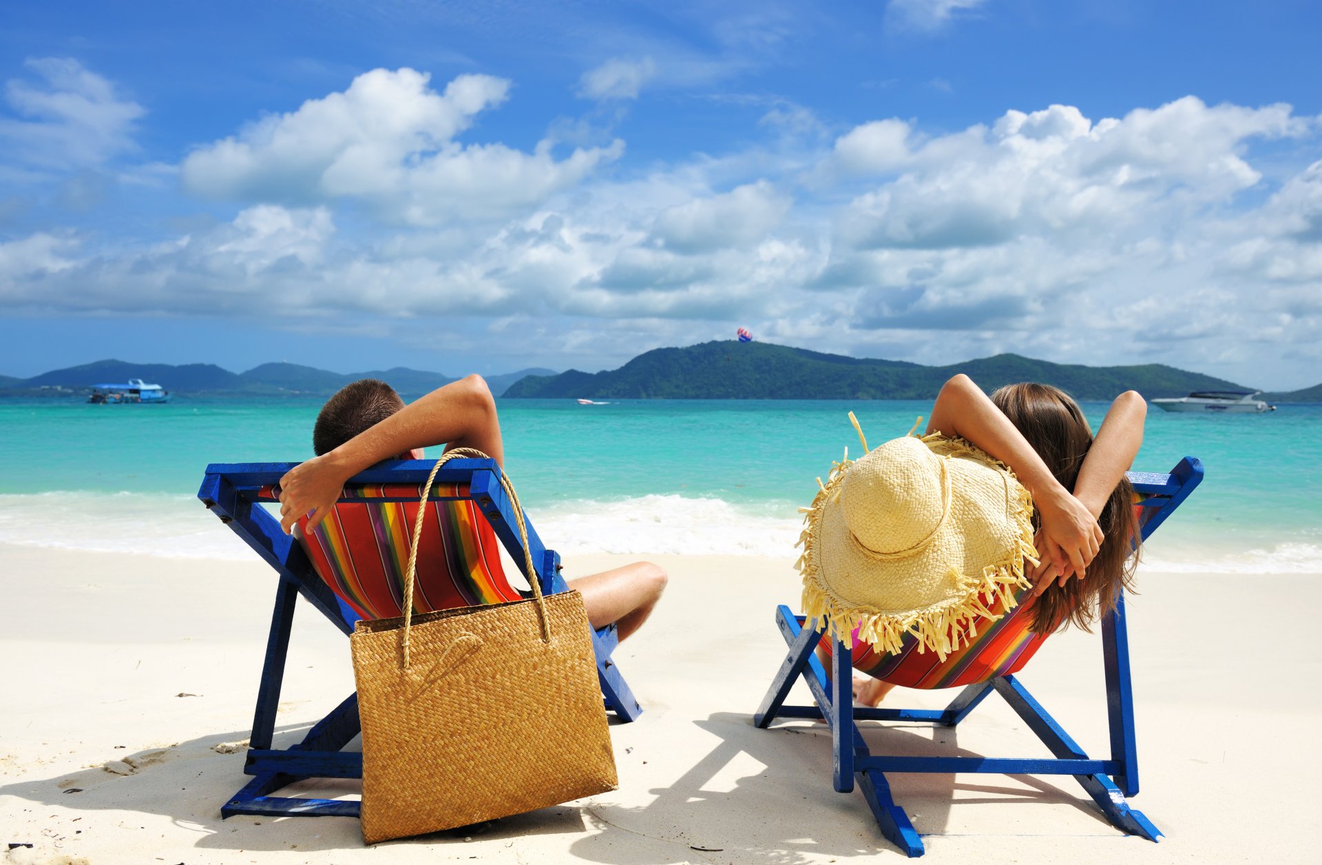 freizeit entspannen mann frau junge mädchen strand sand meer wasser himmel wolken inseln strandstühle tasche hut sommer boote tropisch landschaft natur