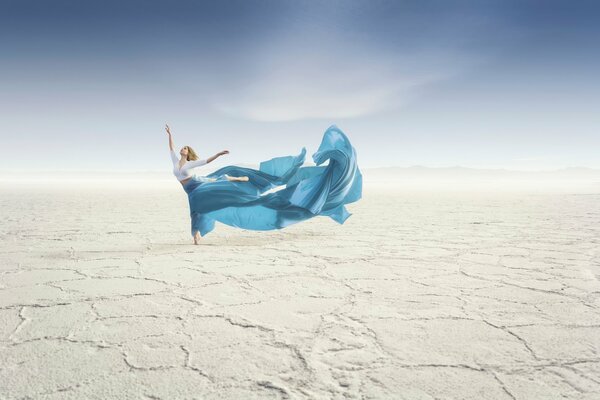 Dancing girl in the desert with a blue long skirt