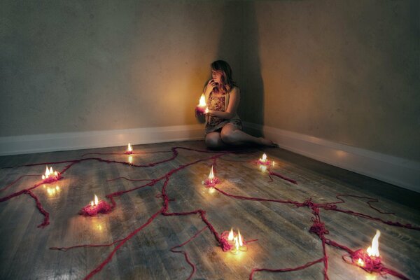 A girl in the corner of the room with a candle in her hands