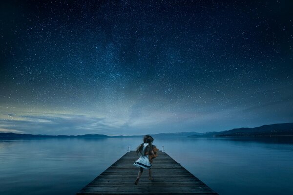 Chica en el muelle en el cielo estrellado