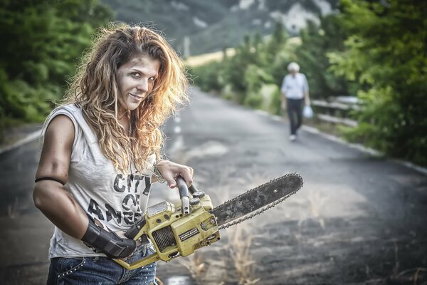 Ragazza in mano con una motosega in montagna