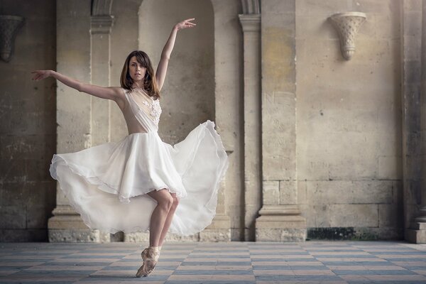 Bella ballerina in abito bianco in un vecchio edificio