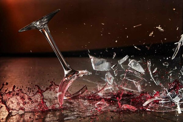 A glass of red wine smashing on the floor