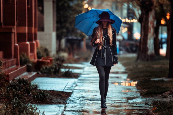 Das Mädchen unter dem Regenschirm geht in den Regen