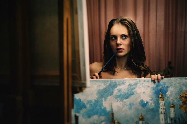 The girl holds a picture on which the temple is painted