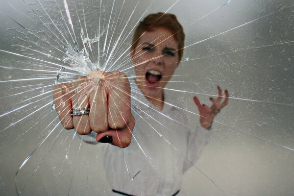 A mad girl hits the glass with her fist