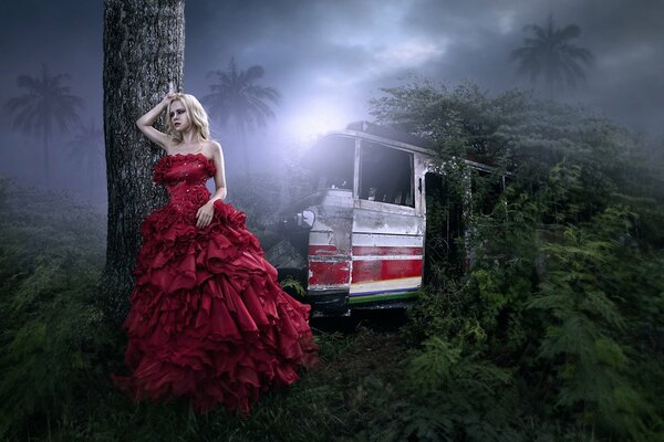 A girl in a red dress in a dark jungle