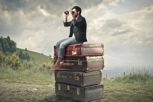 A man on suitcases with binoculars