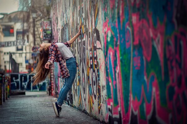 Chica en la ciudad cerca de un hermoso graffiti