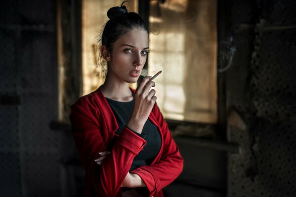 La fille en rouge avec une cigarette sur les mains