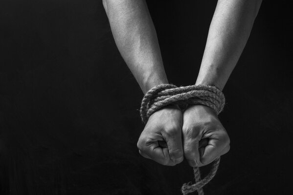 Hands shrouded in shackles on a black background