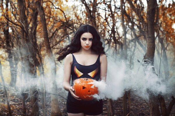 Fille avec une tête de citrouille dans la fumée