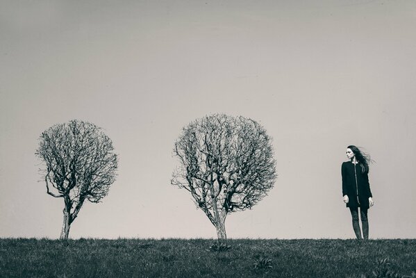 Black and white photo of a girl and two lonely trees