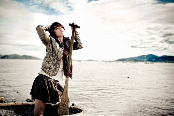 A girl is standing in a boat with an oar