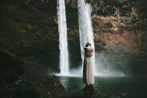 Mädchen steht im Wasser in der Nähe eines Wasserfalls