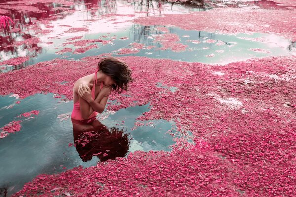 Chica en el agua con pétalos de rosa