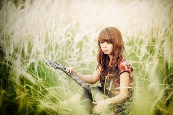 Asiatische Frau auf dem Feld mit Gitarre