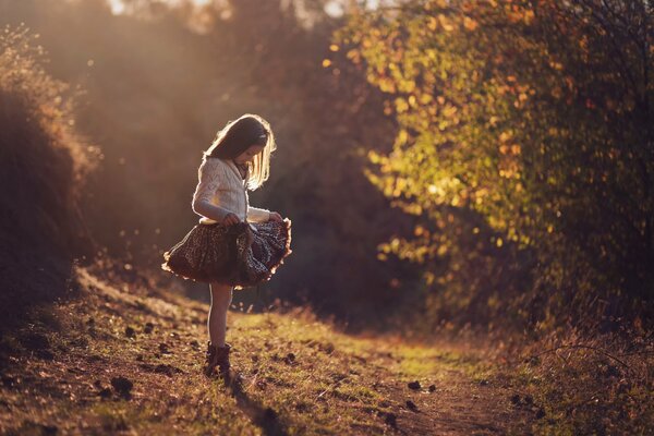 Mädchen in einem schönen Kleid im Herbstwald. Sonnenstrahlen