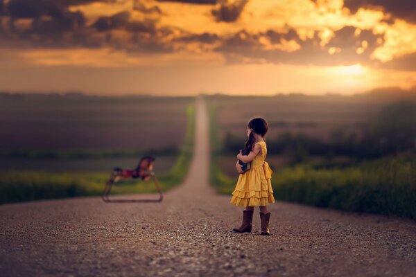 A girl in boots on the road looks at a toy horse