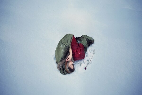 Fille se trouve sur la neige près de la rose rouge