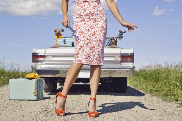 Retro-Auto mit einem Retro-Koffer und einem Mädchen mit einem Schlüssel in der Hand