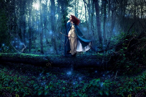 A red-haired girl in the forest with a bow in her hands