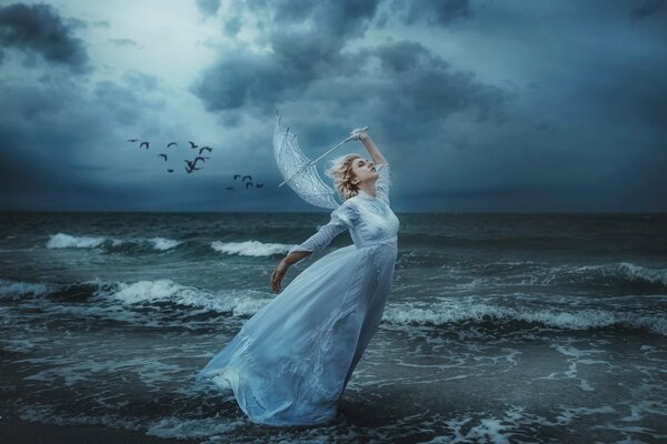 Hada en la orilla del mar durante una tormenta rodeada de aves