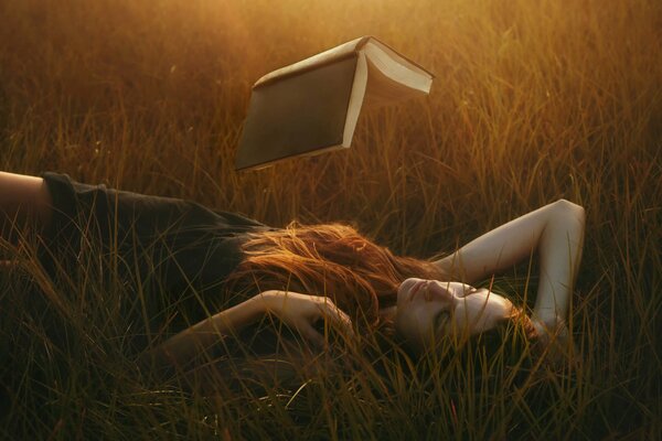 Mädchen liest ein schwebendes Buch im Gras liegend