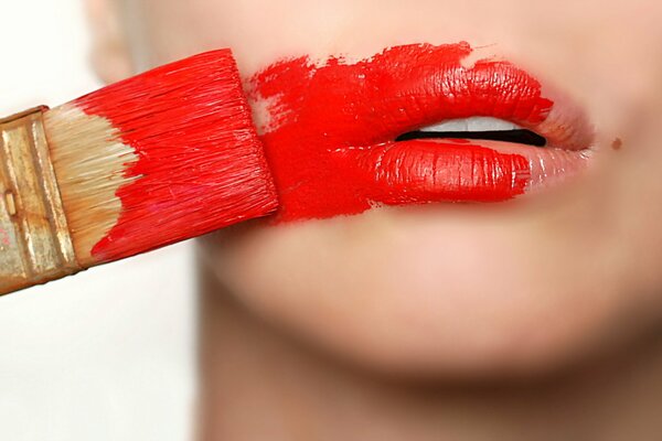 The girl paints her lips with paint