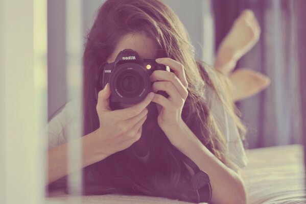 La jeune fille avec un appareil photo se reflète dans le miroir