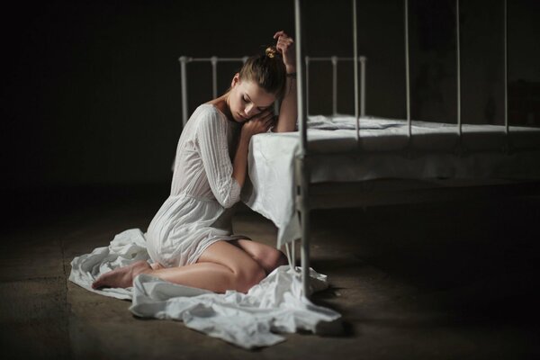 La fille en blanc sur le sol près du lit